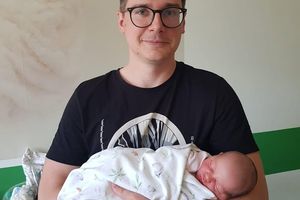 Mężczyzna trzymający noworodka.